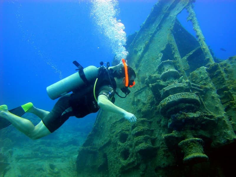 A scuba diver swimming along an underwater shipwreck.